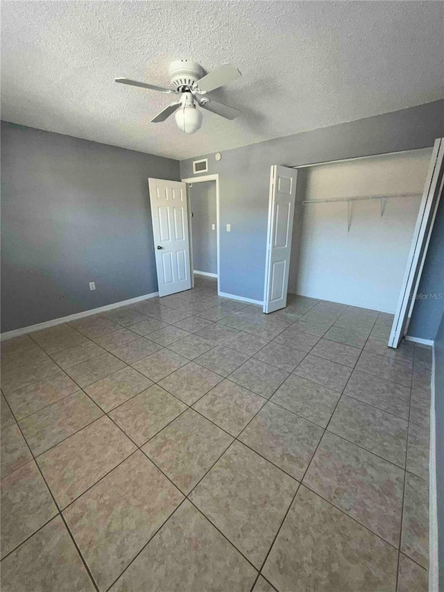 unfurnished bedroom with ceiling fan, light tile patterned flooring, a textured ceiling, and a closet