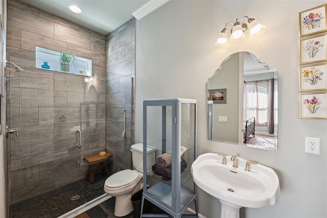 bathroom featuring toilet, a shower with shower door, and sink