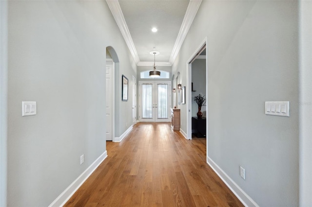 hall with french doors, ornamental molding, and light hardwood / wood-style floors