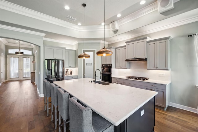 kitchen featuring french doors, sink, decorative light fixtures, appliances with stainless steel finishes, and a kitchen island with sink