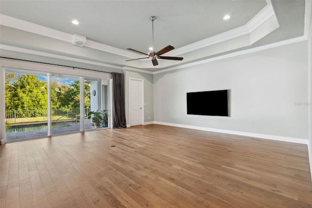 unfurnished living room with ceiling fan, ornamental molding, a raised ceiling, and light hardwood / wood-style floors