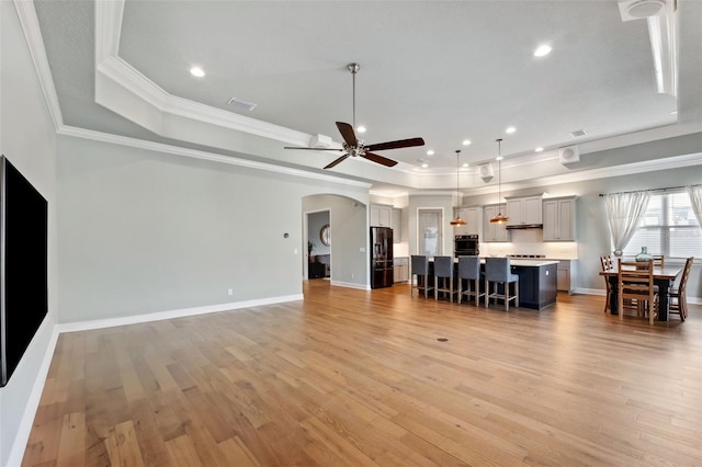 living room with a raised ceiling, crown molding, ceiling fan, and light wood-type flooring