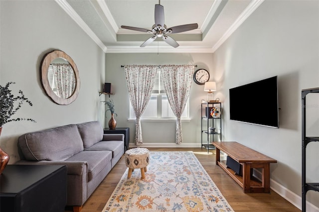 living room featuring ornamental molding, ceiling fan, light hardwood / wood-style floors, and a tray ceiling