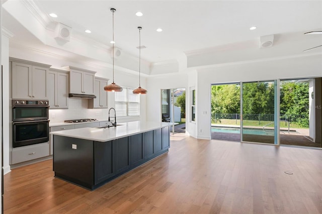 34 Concord Dr, Dunedin, FL 34698 - kitchen featuring a sink, a tray ceiling, ornamental molding, light countertops, and decorative backsplash