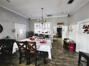 dining room with a notable chandelier, dark hardwood / wood-style flooring, and ornamental molding