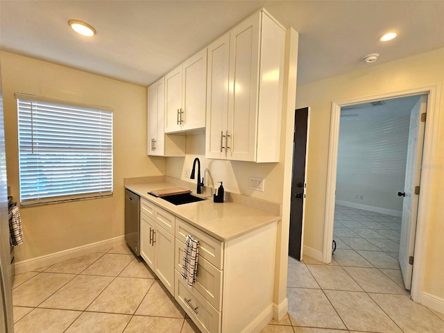 kitchen with dishwasher, white cabinetry, sink, and light tile patterned floors