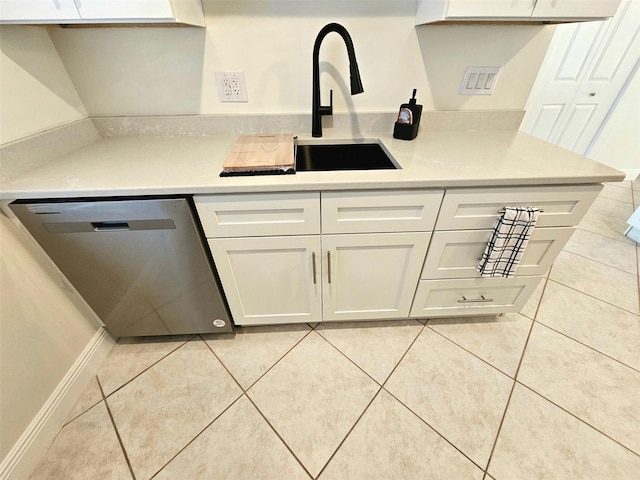 kitchen with white cabinets, light tile patterned floors, stainless steel dishwasher, and sink