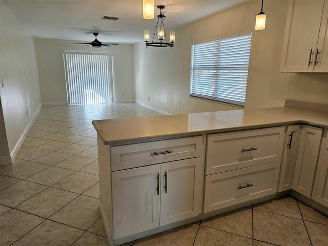 kitchen featuring white cabinets, light tile patterned floors, hanging light fixtures, and ceiling fan with notable chandelier