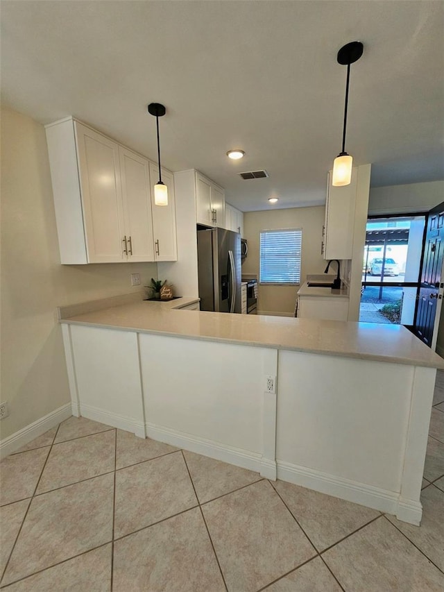 kitchen featuring white cabinets, stainless steel refrigerator with ice dispenser, kitchen peninsula, decorative light fixtures, and light tile patterned flooring