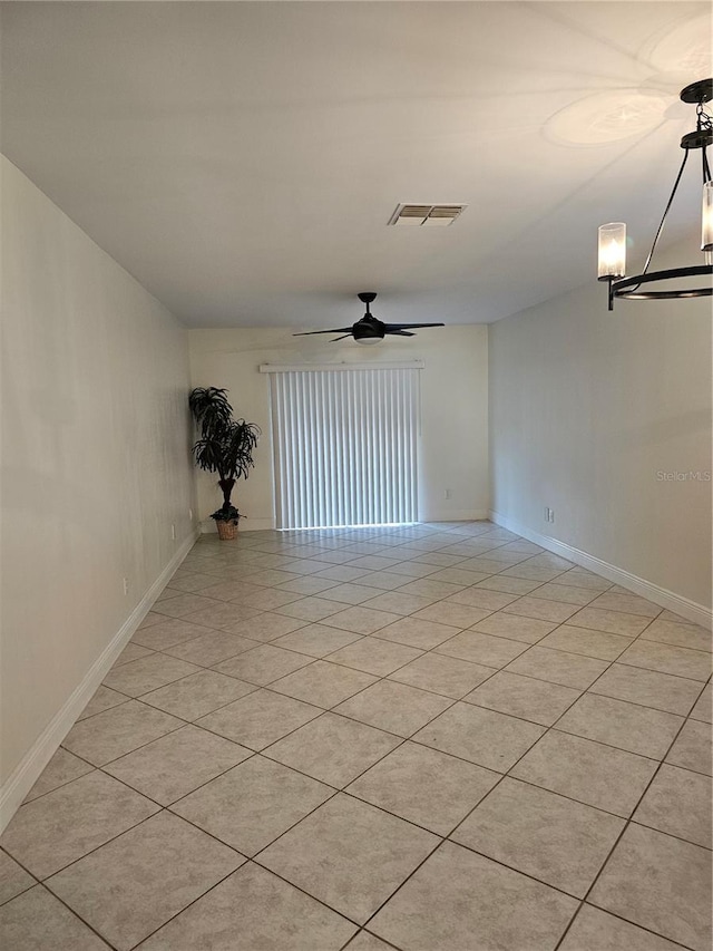 tiled empty room featuring ceiling fan with notable chandelier