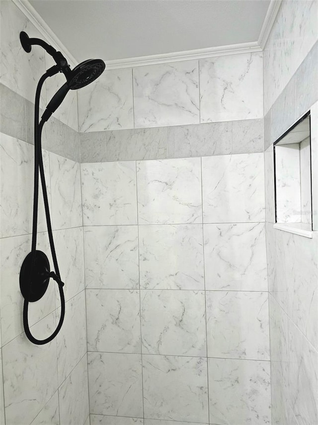 interior details with a tile shower and ornamental molding