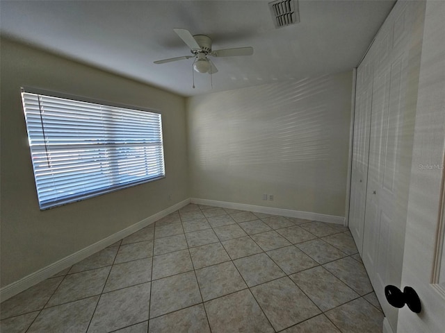 tiled spare room featuring ceiling fan