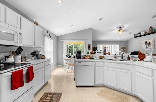 kitchen with vaulted ceiling, white cabinetry, sink, and white appliances