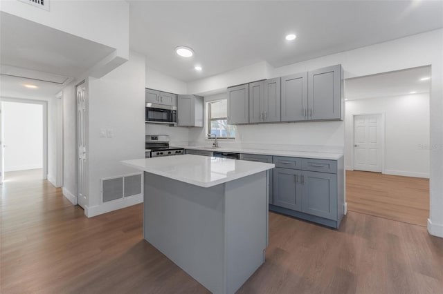 kitchen featuring sink, gray cabinetry, stainless steel appliances, a kitchen island, and dark hardwood / wood-style flooring