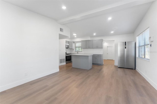 kitchen featuring vaulted ceiling with beams, a center island, light hardwood / wood-style flooring, appliances with stainless steel finishes, and gray cabinets