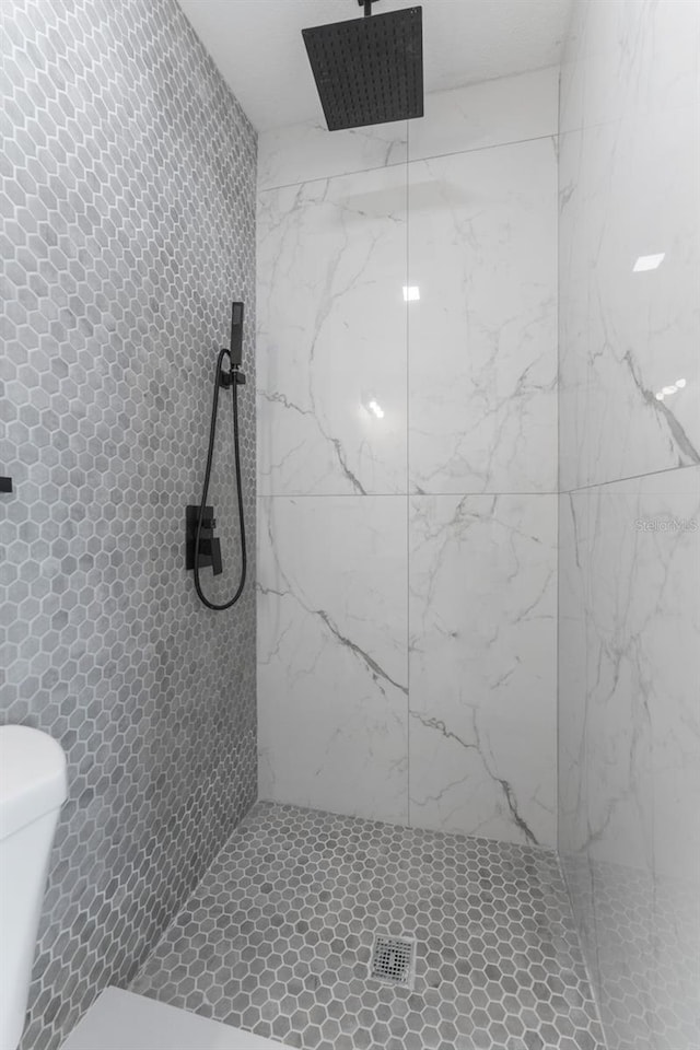 bathroom featuring toilet and a tile shower