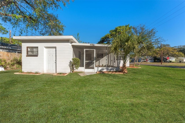 back of property with a sunroom and a lawn