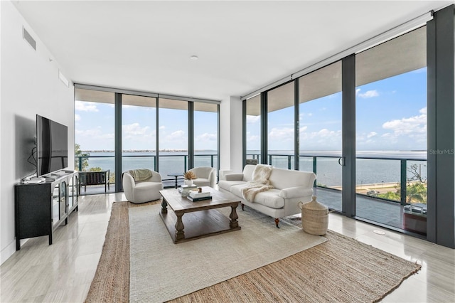 living room with a wealth of natural light, light wood-type flooring, and a wall of windows