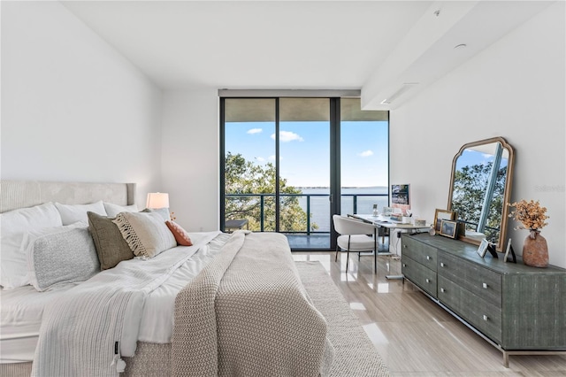 bedroom with access to exterior, a wall of windows, and multiple windows