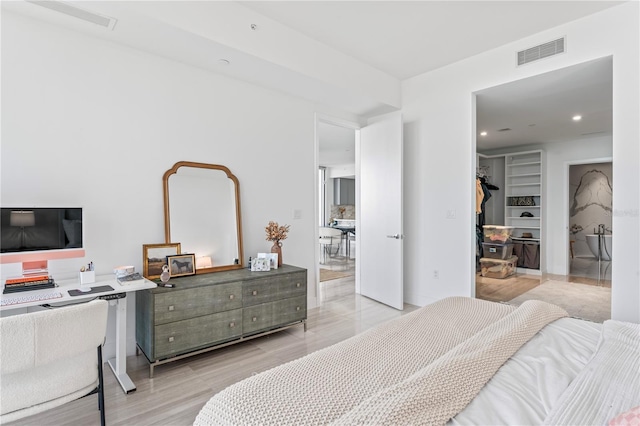 bedroom with a walk in closet, a closet, and light hardwood / wood-style flooring