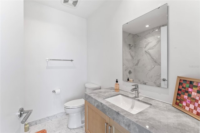 bathroom with tiled shower, vanity, and toilet