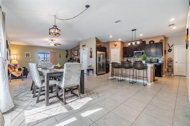 tiled dining space with ceiling fan with notable chandelier