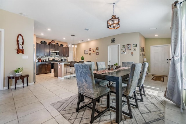 tiled dining room with vaulted ceiling and an inviting chandelier