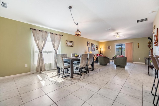 dining space with plenty of natural light, light tile patterned floors, and ceiling fan with notable chandelier