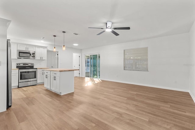 kitchen with wood counters, white cabinets, hanging light fixtures, light hardwood / wood-style flooring, and stainless steel appliances