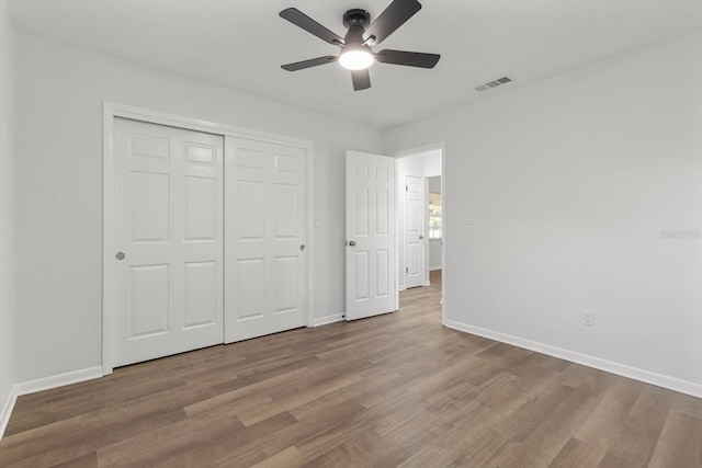 unfurnished bedroom featuring ceiling fan, a closet, and light wood-type flooring