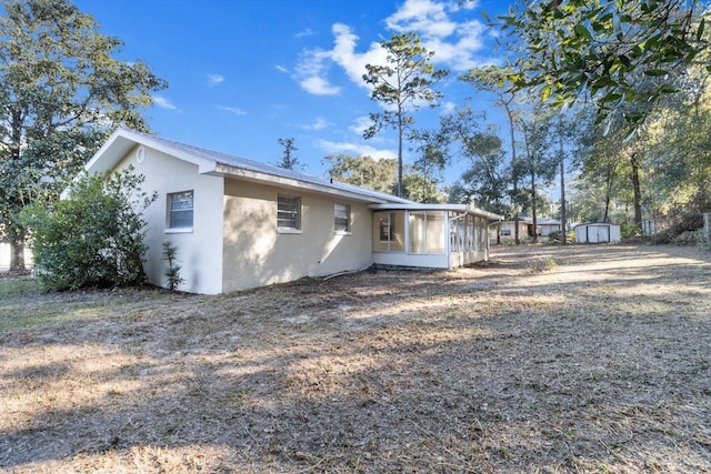 back of property with a storage shed and a sunroom