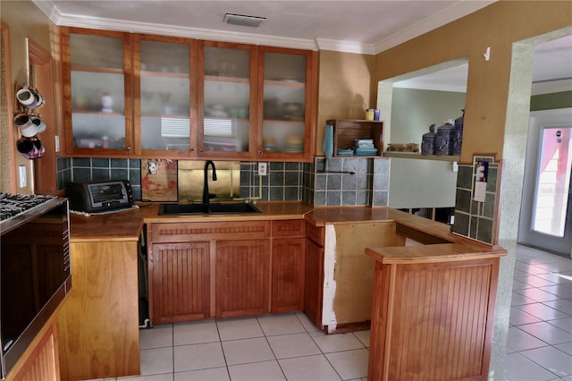 kitchen featuring backsplash, light tile patterned flooring, crown molding, and sink