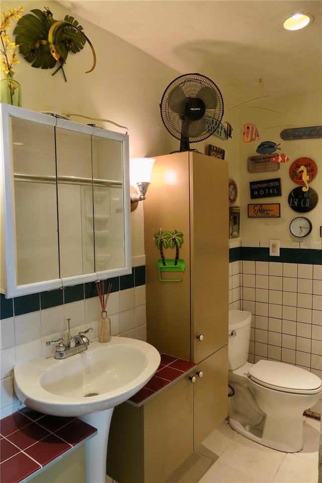 bathroom featuring tile patterned floors, sink, tile walls, and toilet