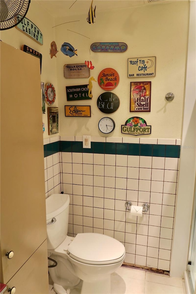 bathroom featuring tile patterned floors, toilet, and tile walls