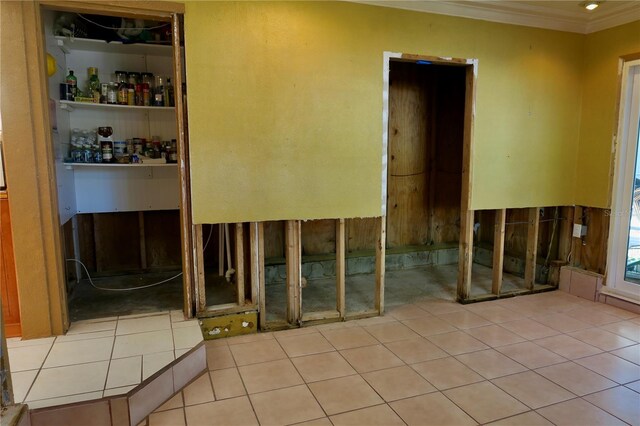 interior space with crown molding, light tile patterned flooring, and indoor bar