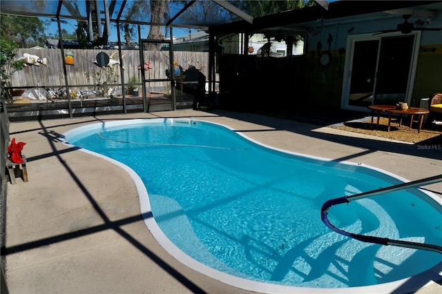 view of swimming pool with a patio, glass enclosure, and ceiling fan