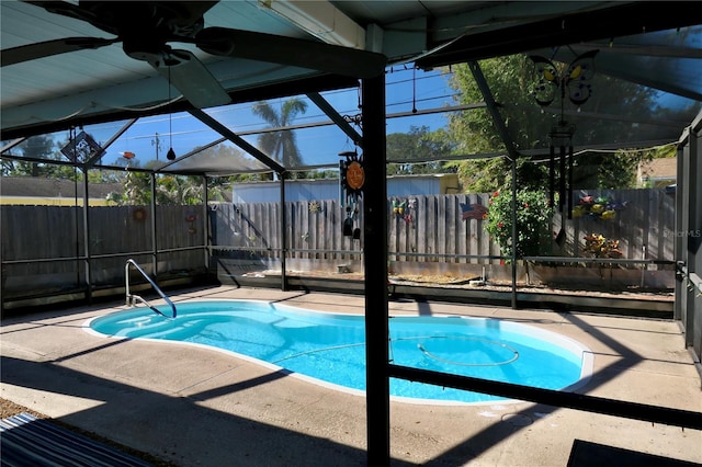 view of swimming pool with glass enclosure, ceiling fan, and a patio area