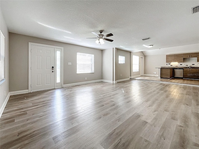 unfurnished living room with ceiling fan, light hardwood / wood-style floors, and a textured ceiling