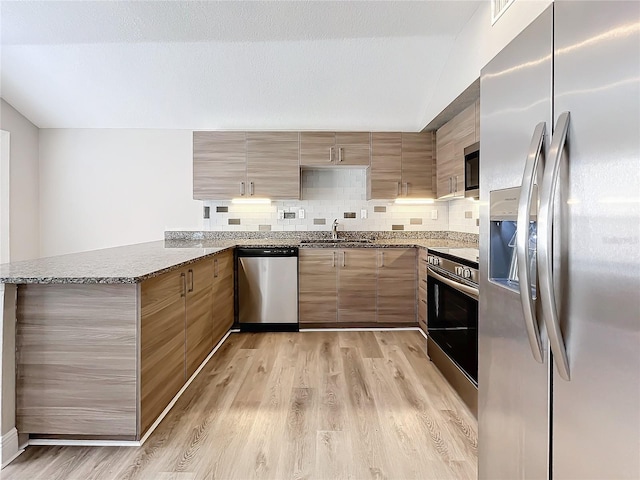 kitchen with sink, decorative backsplash, light hardwood / wood-style floors, kitchen peninsula, and stainless steel appliances