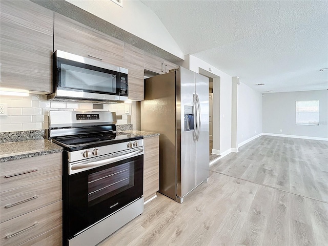 kitchen with appliances with stainless steel finishes, backsplash, light hardwood / wood-style floors, and a textured ceiling