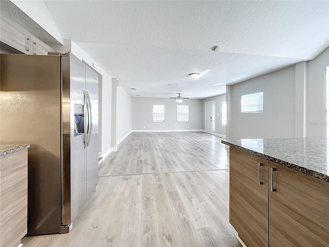 unfurnished living room featuring ceiling fan, light hardwood / wood-style flooring, and a textured ceiling