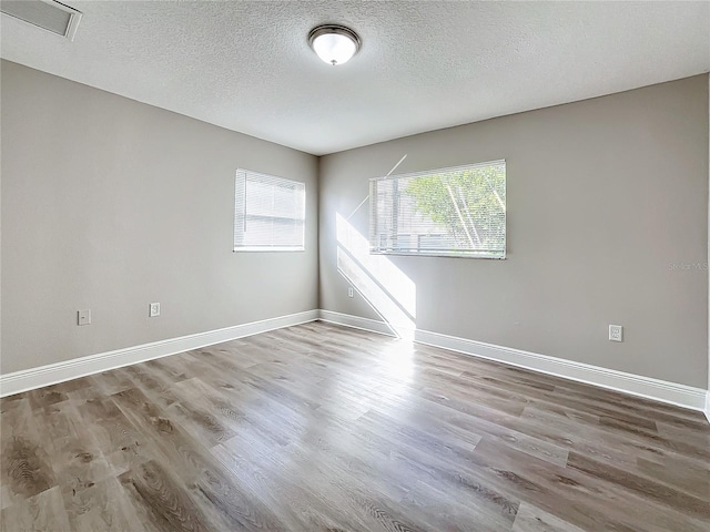 empty room with a textured ceiling and light wood-type flooring