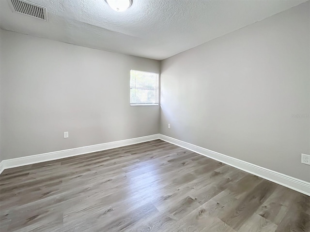 unfurnished room featuring wood-type flooring and a textured ceiling