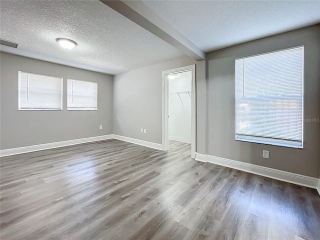 empty room featuring hardwood / wood-style floors, a textured ceiling, and a healthy amount of sunlight