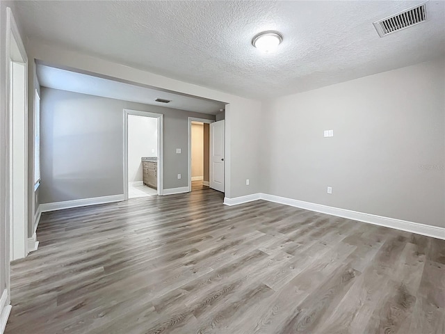 empty room with a textured ceiling and hardwood / wood-style flooring