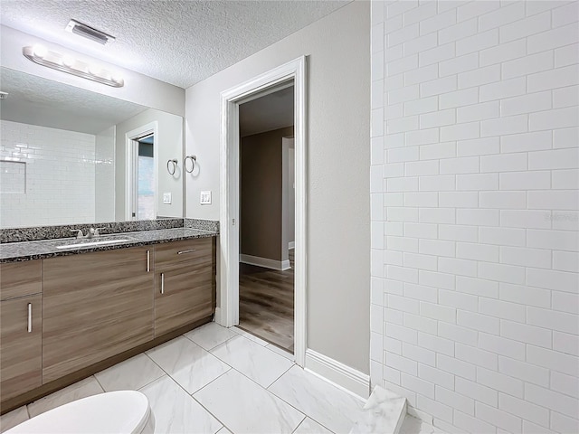 bathroom with vanity, hardwood / wood-style flooring, toilet, a textured ceiling, and a tile shower