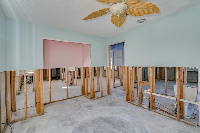 miscellaneous room with ceiling fan, a textured ceiling, and concrete floors