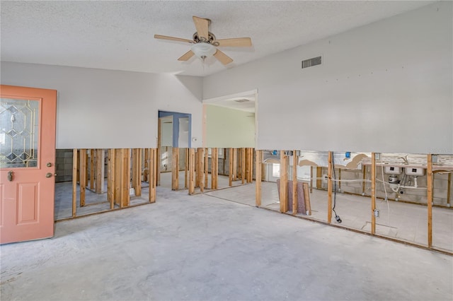 spare room with a wealth of natural light, ceiling fan, concrete floors, and a textured ceiling