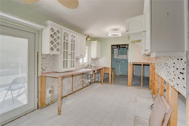 kitchen featuring decorative backsplash, light tile patterned floors, and white cabinetry