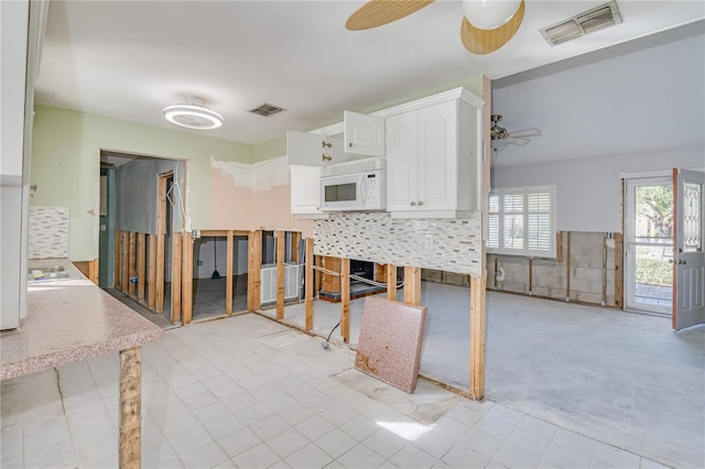 kitchen featuring ceiling fan and white cabinets